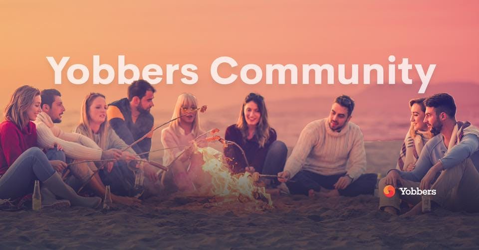 Mädels und Jungs sitzen am Strand an einem Lagerfeuer und halten Stöcke mit Marshmallows