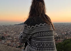 Mädchen sitzt auf einem Berg über Barcelona bei Sonnenuntergang