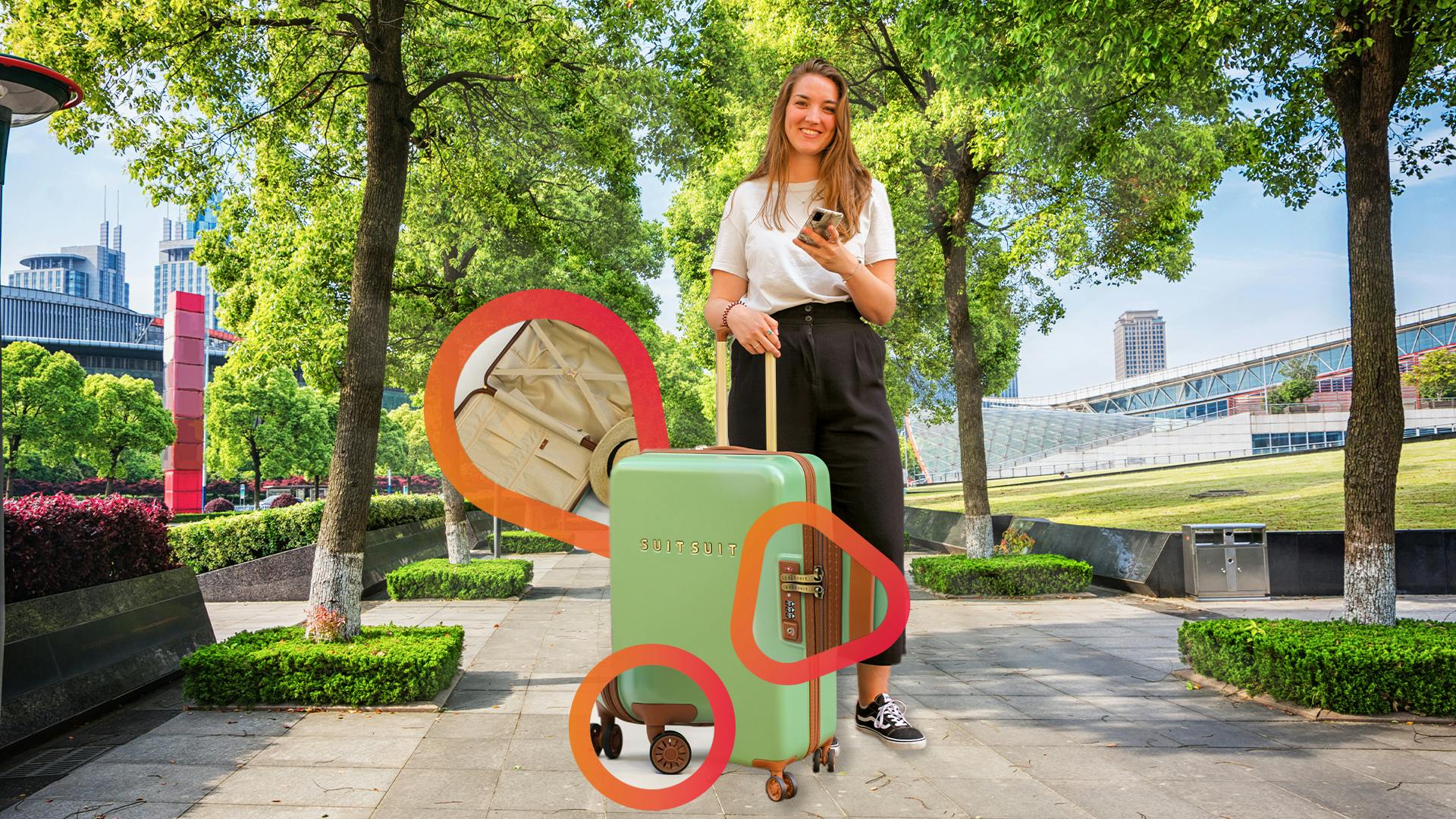 Mädchen mit einem Koffer und Handy in der Hand neben grünen Bäumen