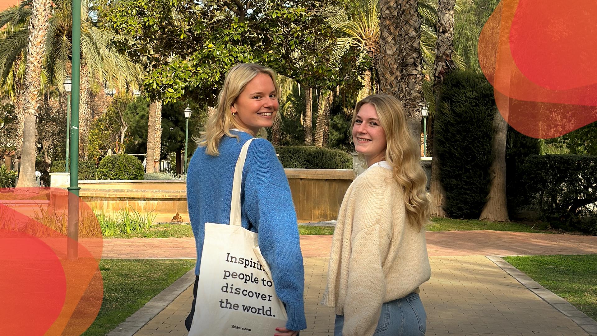 two girls walking next to each other in the park looking into the camera