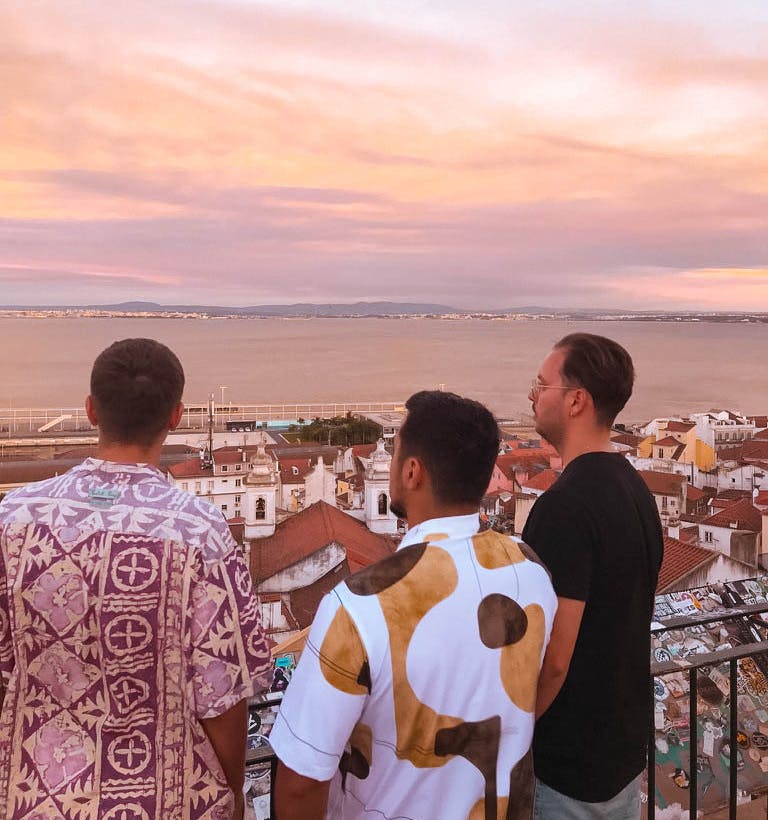 Männer schauen den Sonnenuntergang über den Dächern von Lissabon an