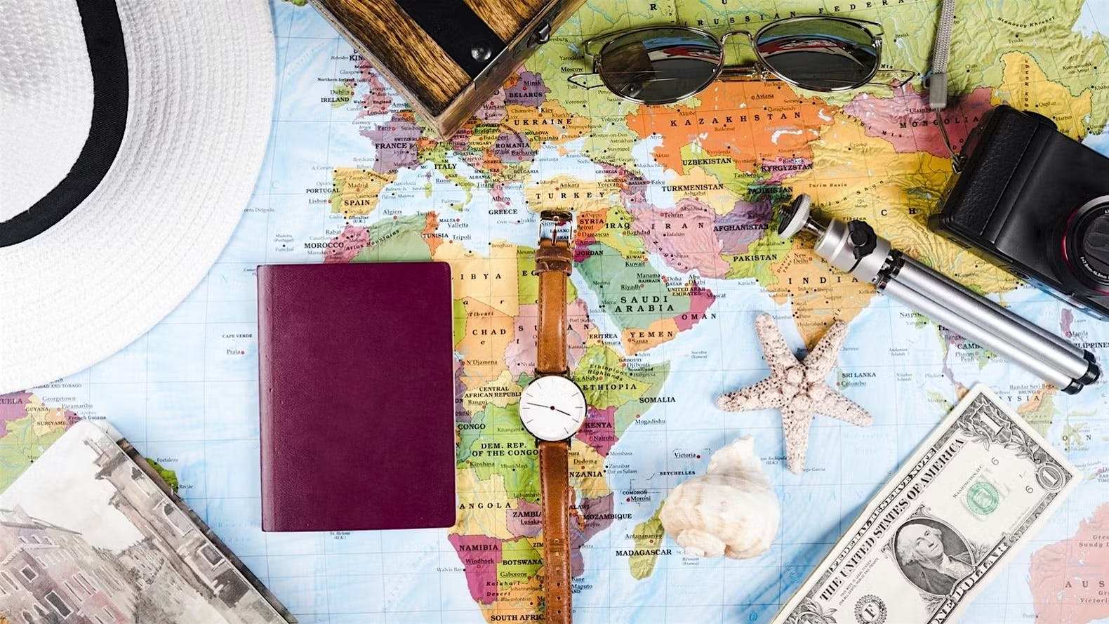 Watch, passport and travel utensils on a world map