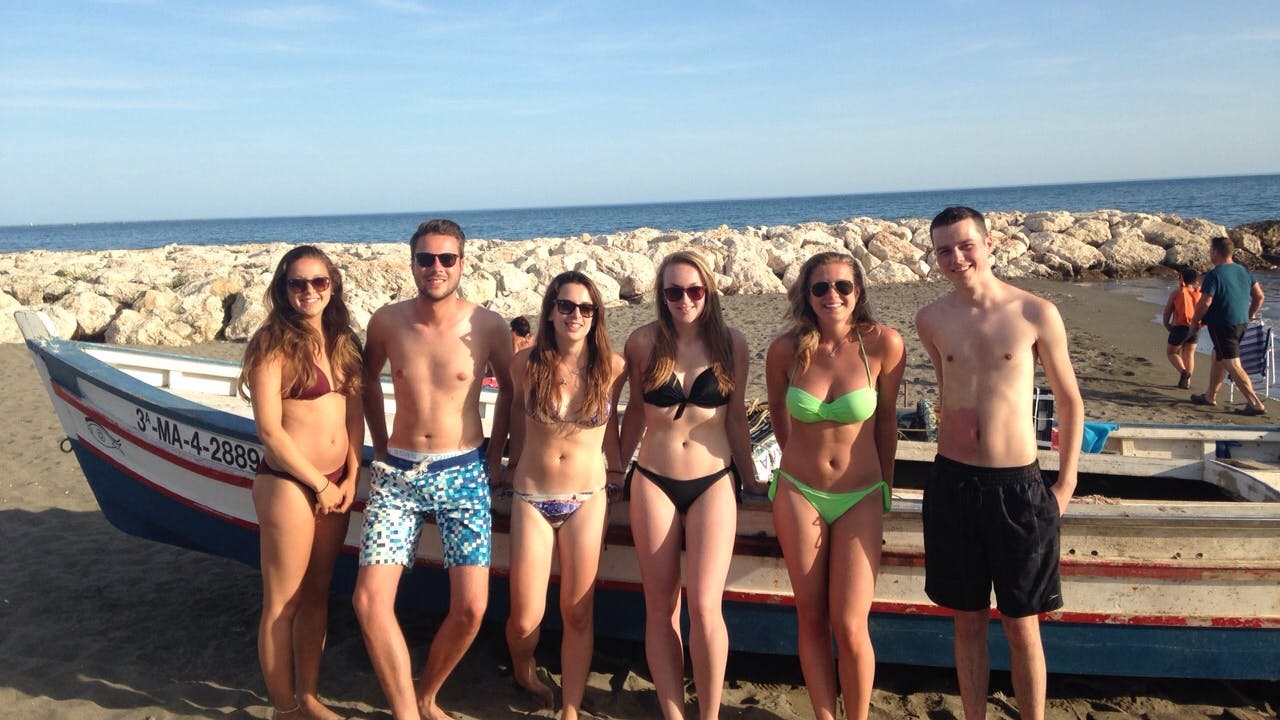 a group of girls and guys standing next to each other at the beach