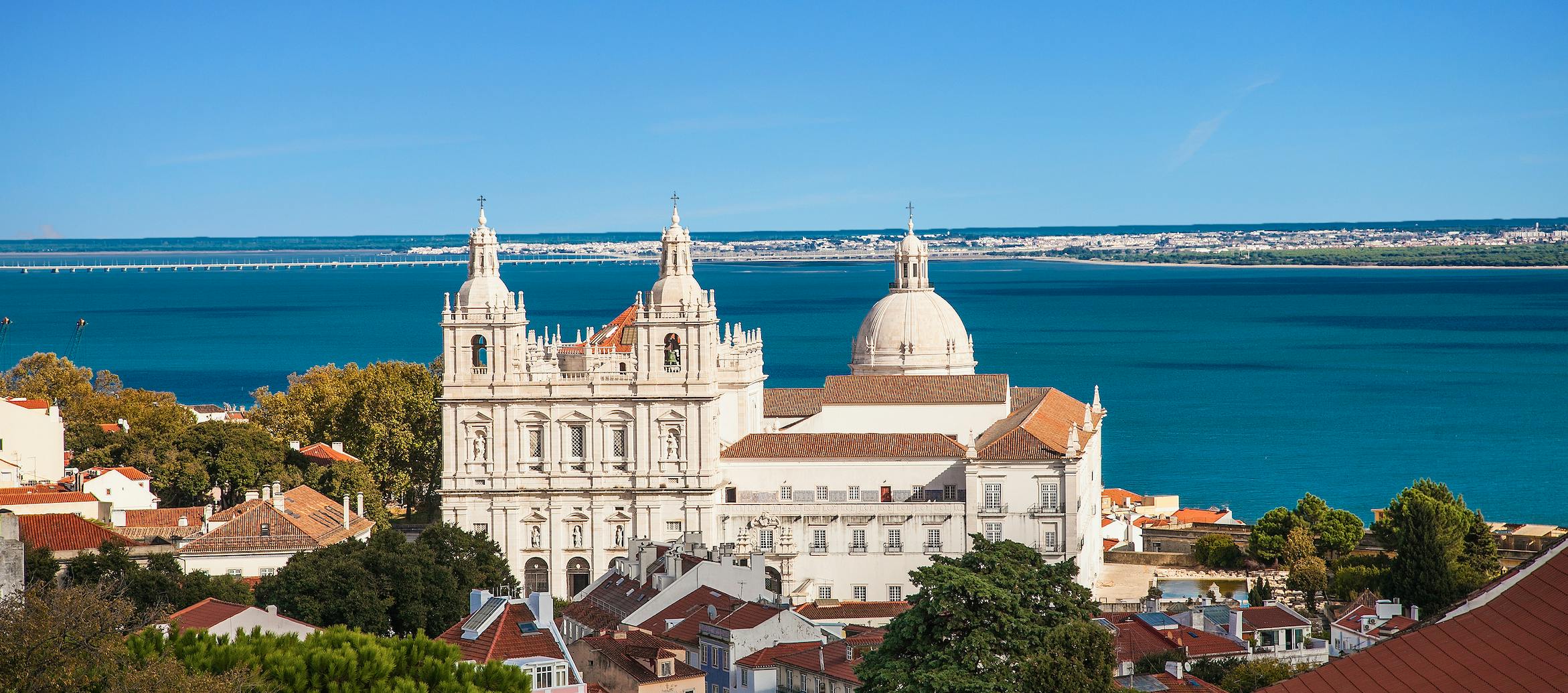 weißes Haus auf einem hügel mit einem ausblick auf das meer und blauem himmel