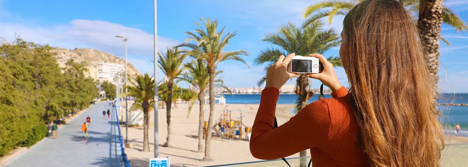 frau steht an einem strand und macht ein foto bei blauem himmel