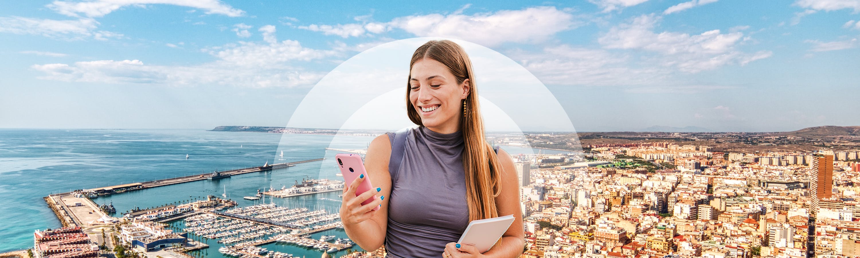 Meisje met zwarte koptelefoon, roze telefoon en op de achtergrond de haven van Alicante