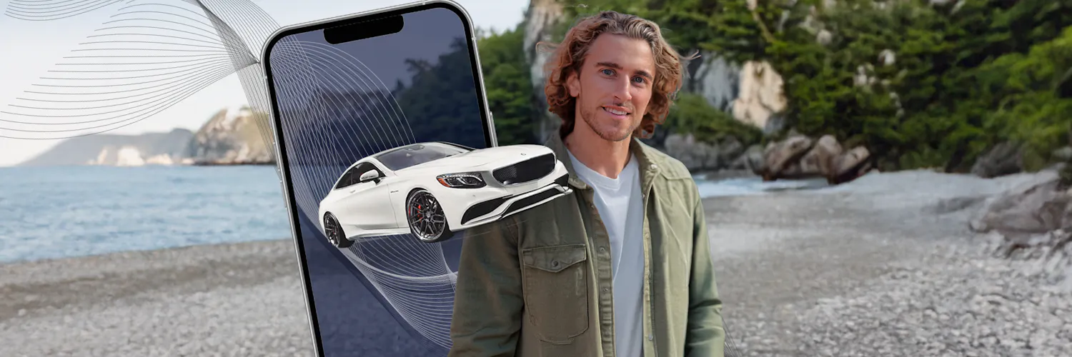 junger Mann vor einem handy auf dem ein Mercedes zu sehen ist